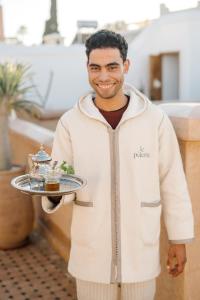 un homme tenant un plateau avec de la nourriture dans l'établissement Riad Le Pèlerin, à Marrakech