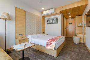a bedroom with a bed and a desk and a table at Ginger Surat City Centre in Surat