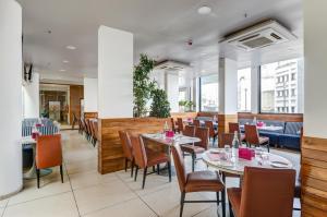 a dining room with tables and chairs and windows at Ginger Surat City Centre in Surat