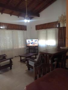 ein Wohnzimmer mit einem TV sowie Tischen und Stühlen in der Unterkunft casa emilia in Villa Gesell