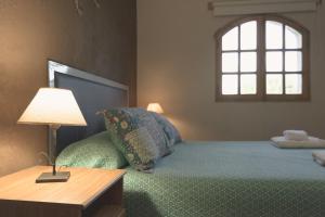 a bedroom with a bed with a lamp and a window at Apart Hotel La Bodega in San Rafael
