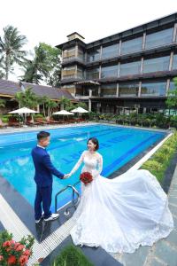 a bride and groom holding hands in front of a pool at Qualia Resort Phu Quoc in Phú Quốc