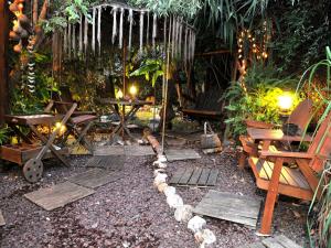 un jardín con bancos de madera, mesa y sillas en צימר בגליל אביב בבקתה, en Galilea