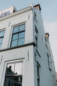 ein weißes Gebäude mit Seitenfenstern in der Unterkunft Brass in Utrecht