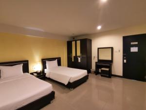 a hotel room with two beds and a mirror at Phupara Place SHA Certified in Phuket Town