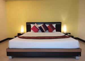a bedroom with a large white bed with red pillows at Phupara Place SHA Certified in Phuket Town
