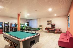 a room with a pool table and arcade games at Hotel Resort Al Sole in Canazei