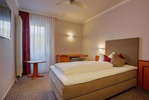 ein Hotelzimmer mit einem großen Bett und einem Schreibtisch in der Unterkunft Hotel Victoria in Bad Kreuznach