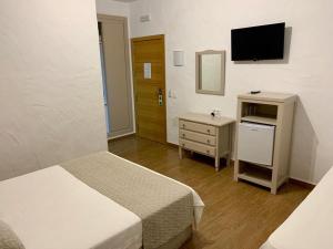a hotel room with a television and a bed at Hotel Almadrabeta in Zahara de los Atunes