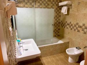 a bathroom with a sink and a tub and a toilet at Hotel Almadrabeta in Zahara de los Atunes