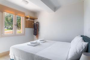 a white bedroom with a bed and a window at Naftilos Residences I in Potokáki