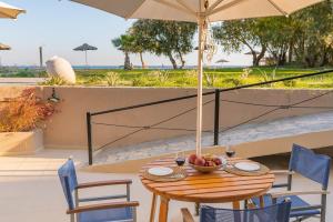 a wooden table with a bowl of fruit and an umbrella at Naftilos Residences I in Potokáki