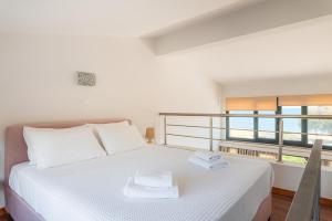 a white bed in a room with a large window at Naftilos Residences I in Potokáki