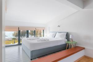 a white bedroom with a large bed and a window at Naftilos Residences I in Potokáki