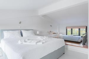 a white bedroom with a white bed and a mirror at Naftilos Residences I in Potokáki