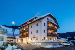 a large white building with cars parked in a parking lot at Nei Y Suredl NeveSole in Corvara in Badia