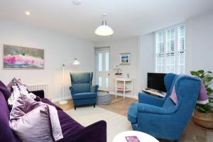 a living room with two blue chairs and a tv at ALTIDO Vibrant 2 Bedroom Apartment in City Centre in Edinburgh