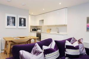 a living room with two purple couches and a kitchen at ALTIDO Vibrant 2 Bedroom Apartment in City Centre in Edinburgh