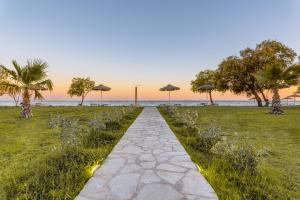 a walkway with umbrellas in a field with the ocean at Naftilos Residences I in Potokáki