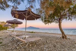 a group of chairs and umbrellas on a beach at Naftilos Residences I in Potokáki