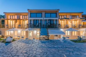 a building with tables and umbrellas in front of it at Naftilos Residences I in Potokáki