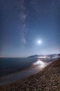 a beach at night with the moon and stars at Naftilos Residences I in Potokáki
