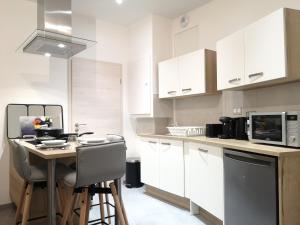 uma cozinha com armários brancos e uma mesa com cadeiras em LE WILSON SUITE - Centre-ville - Gare - Tram em Mulhouse mais 28 fotografias