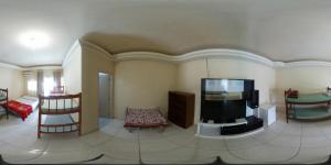 a living room with a flat screen tv and chairs at Pousada Parque Praia in Penha