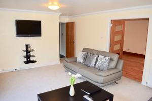 een woonkamer met een bank en een tafel bij Kelpies Serviced Apartments Kavanagh- 5 Bedrooms in Bathgate