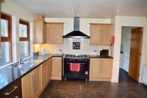 een keuken met houten kasten en een zwarte kookplaat bij Kelpies Serviced Apartments Kavanagh- 5 Bedrooms in Bathgate