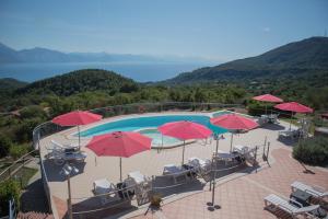 una piscina con sombrillas y sillas rojas en Hotel Caluna Charme, en San Giovanni a Piro