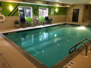 - une grande piscine dans un hôtel avec des chaises et une table dans l'établissement Holiday Inn Express Hotel & Suites St. Paul - Woodbury, an IHG Hotel, à Woodbury