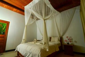 a bedroom with a canopy bed with white curtains at Bintang House in Kintamani