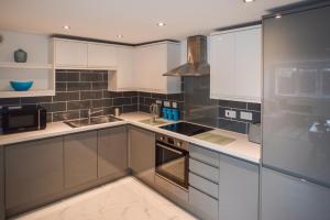 a kitchen with white cabinets and white appliances at Anstey Heights Apartments in Bristol