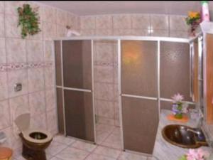 a bathroom with a shower and a toilet and a sink at Pousada Parque Praia in Penha