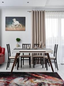 una mesa de comedor con una pintura de caballo blanco en la pared en Goldwell Apartments - Szczesliwa en Żory