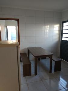 a table and bench in a room with a table and a window at Casa botucatu in Botucatu +3 photos