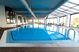 a large pool with blue water in a building at Meliá Castelo Branco in Castelo Branco