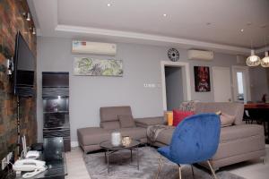 ein Wohnzimmer mit einem Sofa und einem blauen Stuhl in der Unterkunft The Avery Apartments, Dzorwulu in Accra