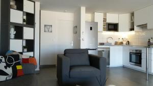 een woonkamer met een stoel en een keuken bij Friendly Beach House in Baie Nettle