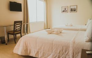 una habitación de hotel con 2 camas y una silla en Villa Oasis en Ica