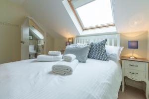 a bedroom with a white bed with towels on it at Curlew's Cwtch in Wadebridge