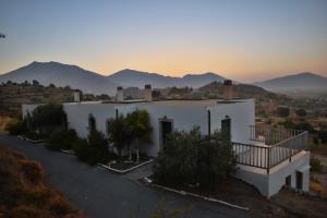 una casa bianca con montagne sullo sfondo di Lasinthos Eco Park ad Áyios Yeóryios