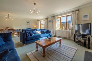 uma sala de estar com sofás azuis e uma televisão em Keepers Cottage em Wadebridge