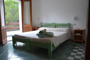 un letto verde in una stanza con finestra di Guardia dei Mori a Carloforte