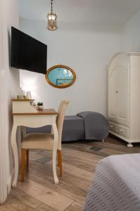 Schlafzimmer mit einem Schreibtisch, einem Bett und einem TV in der Unterkunft Real Giardinetto a Toledo in Neapel