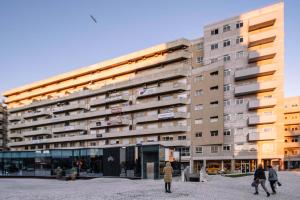 ポルトにあるBBA Apartments Boavista - Casa da Música with Parkingの目の前を歩く人々のいる高い建物
