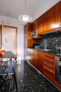 cocina con armarios de madera y encimera en BBA Apartments Boavista - Casa da Música with Parking, en Oporto