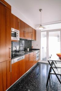 cocina con armarios de madera, fregadero y mesa en BBA Apartments Boavista - Casa da Música with Parking, en Oporto