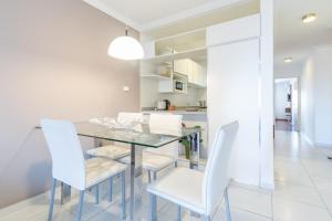 a dining room with a glass table and white chairs at AT Suites in Córdoba